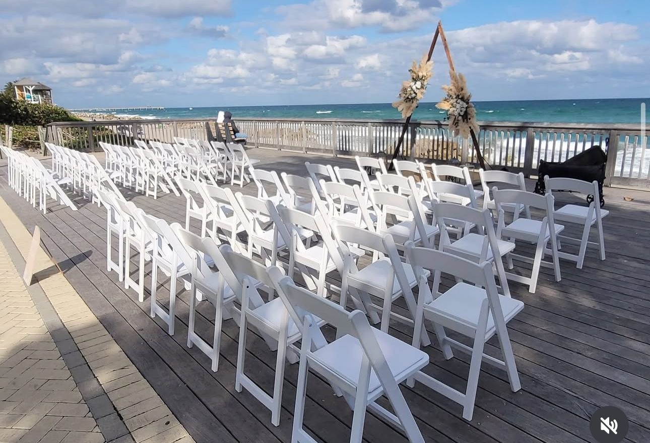An airy ceremony setup with white chairs and a sea view lets the love story take center stage.