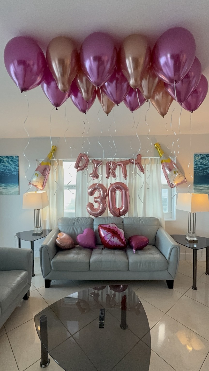 Pink and champagne balloons fill the room with a playful welcome for a milestone birthday.